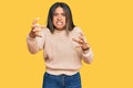 Young latin girl wearing wool winter sweater shouting frustrated with rage, hands trying to strangle, yelling mad Royalty Free Stock Photo