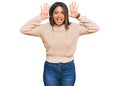 Young latin girl wearing wool winter sweater smiling cheerful playing peek a boo with hands showing face Royalty Free Stock Photo