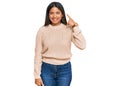 Young latin girl wearing wool winter sweater smiling doing phone gesture with hand and fingers like talking on the telephone Royalty Free Stock Photo