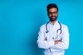 young latin hispanic medican man wear eye glasses with stethoscope in blue studio wall background Royalty Free Stock Photo