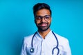 young latin hispanic medican man wear eye glasses with stethoscope in blue studio wall background Royalty Free Stock Photo