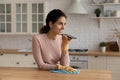 Young latin housewife tidying up kitchen dictate message on phone