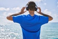Young latin man on back view listening to music using headphones at the beach Royalty Free Stock Photo