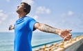 Young latin man breathing using headphones and smartphone at the beach Royalty Free Stock Photo