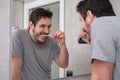 Young latin man brushing his teeth in front of the mirror in the bathroom at morning Royalty Free Stock Photo