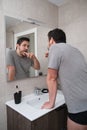 Young latin man brushing his teeth in front of the mirror in the bathroom at morning Royalty Free Stock Photo