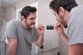 Young latin man brushing his teeth in front of the mirror in the bathroom at morning Royalty Free Stock Photo