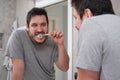 Young latin man brushing his teeth in front of the mirror in the bathroom at morning Royalty Free Stock Photo