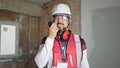 Young latin man builder talking on walkie-talkie at construction site Royalty Free Stock Photo