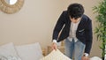 Young latin man business worker make bed at hotel room Royalty Free Stock Photo