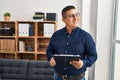 Young latin man business worker smiling confident holding clipboard at office Royalty Free Stock Photo