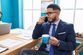Young latin man business worker talking on smartphone drinking coffee at office Royalty Free Stock Photo