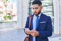 Young latin man business worker using smartphone with serious expression at street Royalty Free Stock Photo