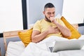 Young latin man coughing having telemedicine sitting on bed at bedroom Royalty Free Stock Photo