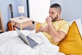 Young latin man coughing having telemedicine sitting on bed at bedroom Royalty Free Stock Photo