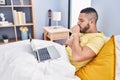 Young latin man coughing having telemedicine sitting on bed at bedroom Royalty Free Stock Photo