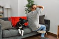 Young latin man and dog sitting on the sofa at home backwards thinking about doubt with hand on head Royalty Free Stock Photo