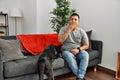 Young latin man and dog sitting on the sofa at home bored yawning tired covering mouth with hand Royalty Free Stock Photo