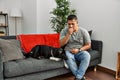 Young latin man and dog sitting on the sofa at home feeling unwell and coughing as symptom for cold or bronchitis Royalty Free Stock Photo