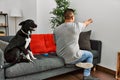 Young latin man and dog sitting on the sofa at home posing backwards pointing ahead with finger hand Royalty Free Stock Photo