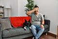 Young latin man and dog sitting on the sofa at home smiling and laughing with hand on face covering eyes for surprise Royalty Free Stock Photo
