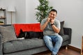 Young latin man and dog sitting on the sofa at home smiling with open mouth, fingers pointing and forcing cheerful smile Royalty Free Stock Photo