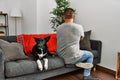 Young latin man and dog sitting on the sofa at home standing backwards looking away with crossed arms Royalty Free Stock Photo