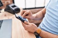 Young latin man ecommerce business worker cleaning screen smartphone at office