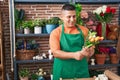 Young latin man florist holding bouquet of flowers at flower shop