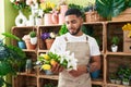 Young latin man florist holding bouquet of flowers at flower shop