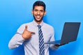 Young latin man holding laptop pointing finger to one self smiling happy and proud