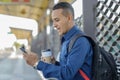 Young latin man looking at his mobile phone with a surprised face a paper cup with coffee in his hand Royalty Free Stock Photo