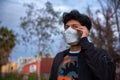 Young latin man with mask is talking on the phone. He is outside his house Royalty Free Stock Photo