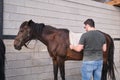 Young latin man putting on the saddle blanket to his horse.