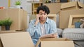 Young latin man reading document talking on smartphone looking upset at new home Royalty Free Stock Photo