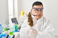 Young latin man scientist looking cannabis herb with loupe at laboratory