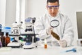 Young latin man scientist looking cannabis herb with loupe at laboratory