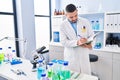 Young latin man scientist writing on notebook at laboratory Royalty Free Stock Photo
