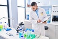 Young latin man scientist writing on notebook at laboratory Royalty Free Stock Photo