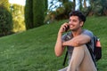 Young latin man sitting in the grass talking by mobile phone. Royalty Free Stock Photo