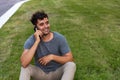 Young latin man sitting in the grass talking by mobile phone. Royalty Free Stock Photo
