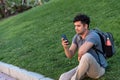 Young latin man sitting in the grass using the mobile phone. Royalty Free Stock Photo