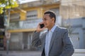 Young latin man sitting on a square bench talking on mobile phone with copy space Royalty Free Stock Photo