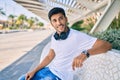 Young latin man smiling happy listening to music using headphones sitting on the bench at the park Royalty Free Stock Photo