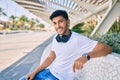 Young latin man smiling happy listening to music using headphones sitting on the bench at the park Royalty Free Stock Photo