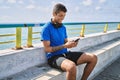 Young latin man smiling happy using headphones and smartphone at the beach Royalty Free Stock Photo