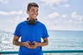 Young latin man smiling happy using headphones and smartphone at the beach Royalty Free Stock Photo