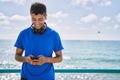 Young latin man smiling happy using headphones and smartphone at the beach Royalty Free Stock Photo