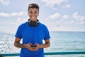 Young latin man smiling happy using headphones and smartphone at the beach Royalty Free Stock Photo