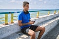 Young latin man smiling happy using headphones and smartphone at the beach Royalty Free Stock Photo